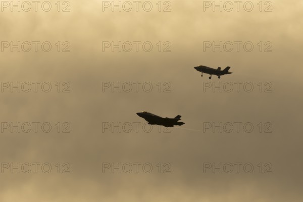 Lockheed Martin F-35 Lightning II fighter two military aircraft of the United States air force USAF silhouette in flight at sunset at RAF Lakenheath airbase, Suffolk, England, United Kingdom