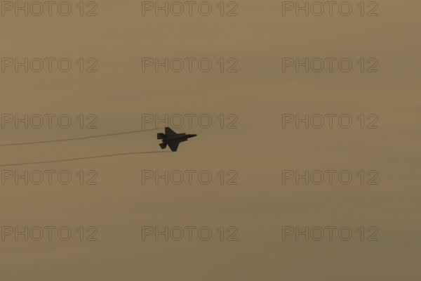 Lockheed Martin F-35 Lightning II fighter military aircraft of the United States air force USAF silhouette in flight at sunset at RAF Lakenheath airbase, Suffolk, England, United Kingdom