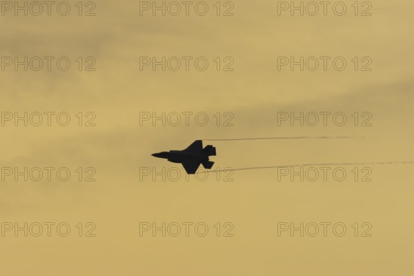 Lockheed Martin F-35 Lightning II fighter military aircraft of the United States air force USAF silhouette in flight at sunset at RAF Lakenheath airbase, Suffolk, England, United Kingdom