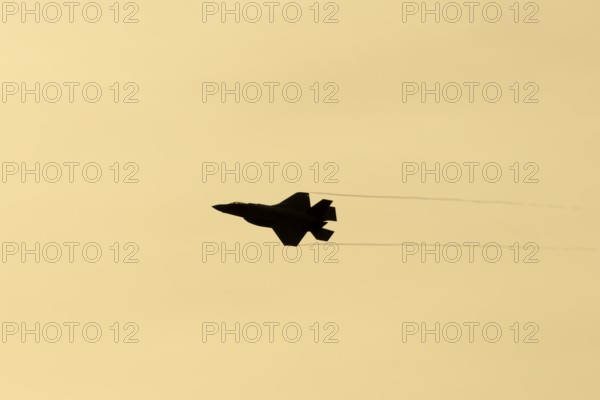 Lockheed Martin F-35 Lightning II fighter military aircraft of the United States air force USAF silhouette in flight at sunset at RAF Lakenheath airbase, Suffolk, England, United Kingdom