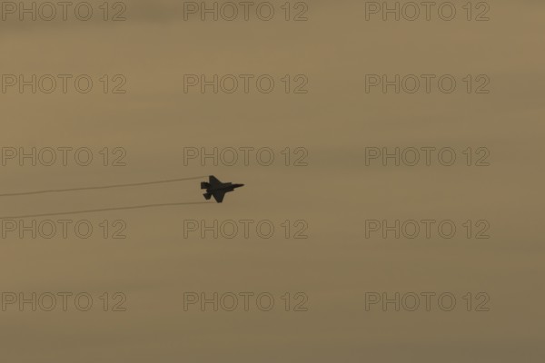 Lockheed Martin F-35 Lightning II fighter military aircraft of the United States air force USAF silhouette in flight at sunset at RAF Lakenheath airbase, Suffolk, England, United Kingdom