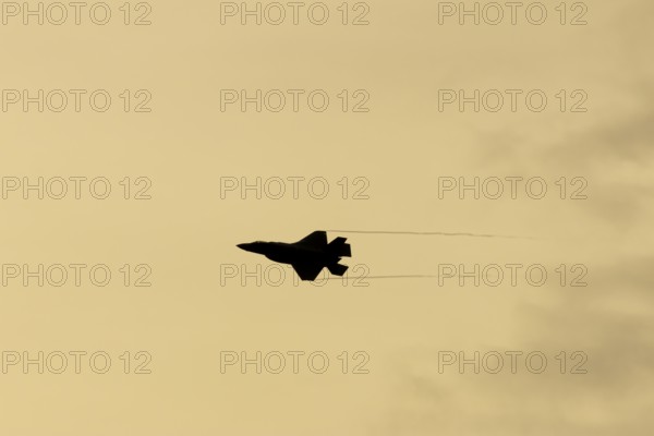 Lockheed Martin F-35 Lightning II fighter military aircraft of the United States air force USAF silhouette in flight at sunset at RAF Lakenheath airbase, Suffolk, England, United Kingdom