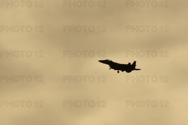 McDonnell Douglas F-15E Strike Eagle fighter military aircraft of the United States air force USAF in flight silhouette at sunset at RAF Lakenheath airbase, Suffolk, England, United Kingdom
