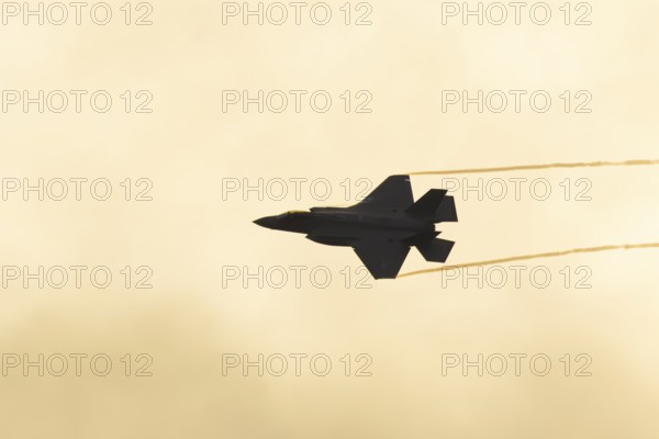 Lockheed Martin F-35 Lightning II fighter military aircraft of the United States air force USAF silhouette in flight at sunset at RAF Lakenheath airbase, Suffolk, England, United Kingdom
