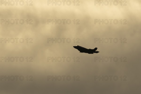Lockheed Martin F-35 Lightning II fighter military aircraft of the United States air force USAF silhouette in flight at sunset at RAF Lakenheath airbase, Suffolk, England, United Kingdom