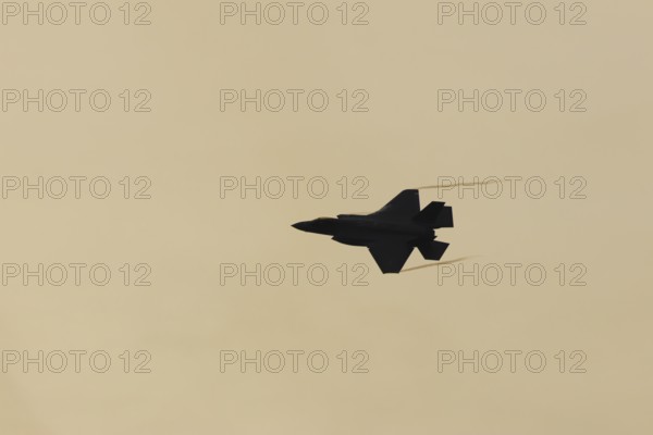 Lockheed Martin F-35 Lightning II fighter military aircraft of the United States air force USAF silhouette in flight at sunset at RAF Lakenheath airbase, Suffolk, England, United Kingdom