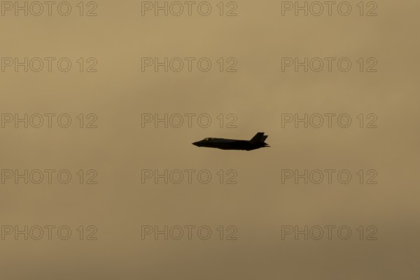 Lockheed Martin F-35 Lightning II fighter military aircraft of the United States air force USAF silhouette in flight at sunset at RAF Lakenheath airbase, Suffolk, England, United Kingdom