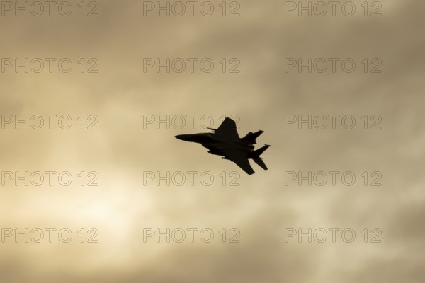 McDonnell Douglas F-15E Strike Eagle fighter military aircraft of the United States air force USAF in flight silhouette at sunset at RAF Lakenheath airbase, Suffolk, England, United Kingdom