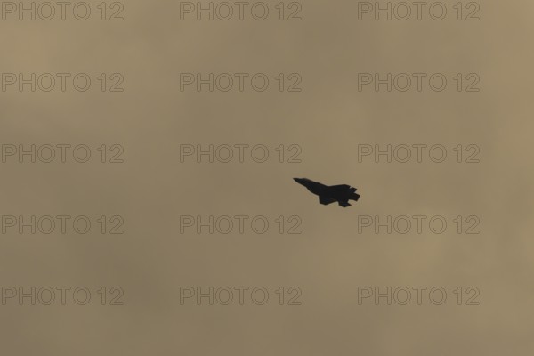 Lockheed Martin F-35 Lightning II fighter military aircraft of the United States air force USAF silhouette in flight at sunset at RAF Lakenheath airbase, Suffolk, England, United Kingdom