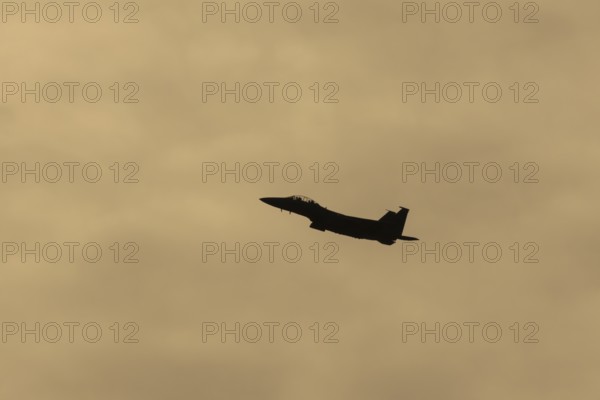McDonnell Douglas F-15E Strike Eagle fighter military aircraft of the United States air force USAF in flight silhouette at sunset at RAF Lakenheath airbase, Suffolk, England, United Kingdom