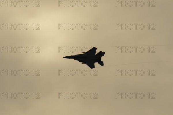 McDonnell Douglas F-15E Strike Eagle fighter military aircraft of the United States air force USAF in flight silhouette at sunset at RAF Lakenheath airbase, Suffolk, England, United Kingdom