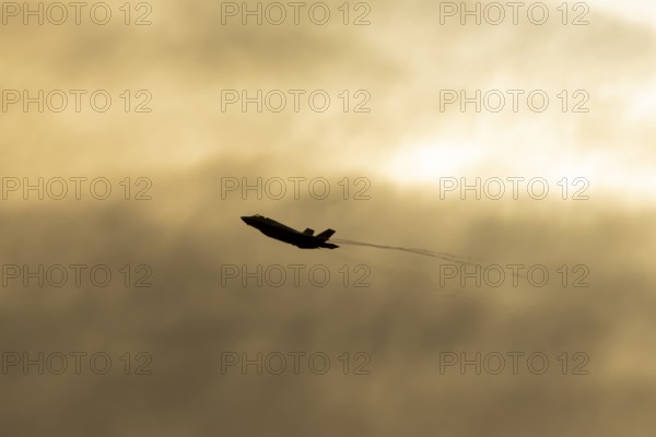 Lockheed Martin F-35 Lightning II fighter military aircraft of the United States air force USAF silhouette in flight at sunset at RAF Lakenheath airbase, Suffolk, England, United Kingdom