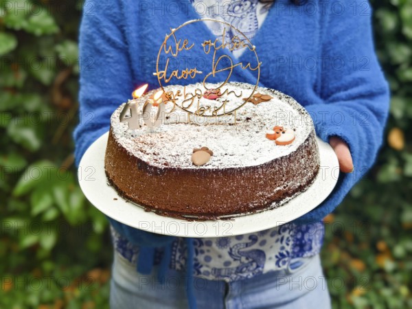 Chocolate cake with birthday decoration and icing held in the hands Lower Austria Austria