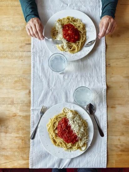 Two plates of spaghetti with tomato sauce and parmesan cheese arranged on a wooden table Lower Austria Austria