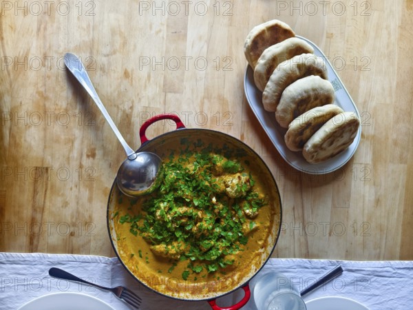 A pot of curry and herbs served with bread on a wooden table Lower Austria Austria