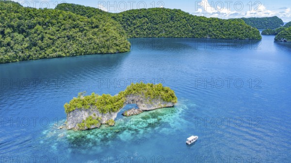 Aerial view bird's eye view of rock arch Natural Arch in lagoon of in island paradise island state Palau in the Pacific West Pacific, in front small boat with tourists, Rock Islands, Republic of Palau, Micronesia, Australia, Oceania