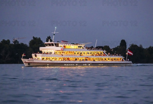 Brightly illuminated passenger ship VORARLBERG underway on Lake Constance during the blue hour. Immenstaad, Baden-Württemberg, Germany