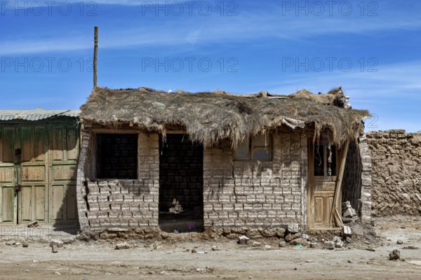 Abandoned hut with a thatched roof and mud bricks under a clear blue sky, a village on the Altiplano plateau in Bolivia
