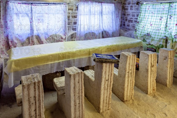 Long stone table with matching stone chair set in a bright, rustic room with patterned curtains, The salt hotel in the salt plain of the Salar de Uyuni in Bolivia