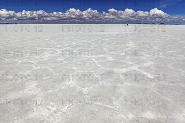 Salt crust with hexagonal patterns under a sky full of clouds, conveying endless expanses, The endless expanses of the salt plain of the Salar de Uyuni in Bolivia