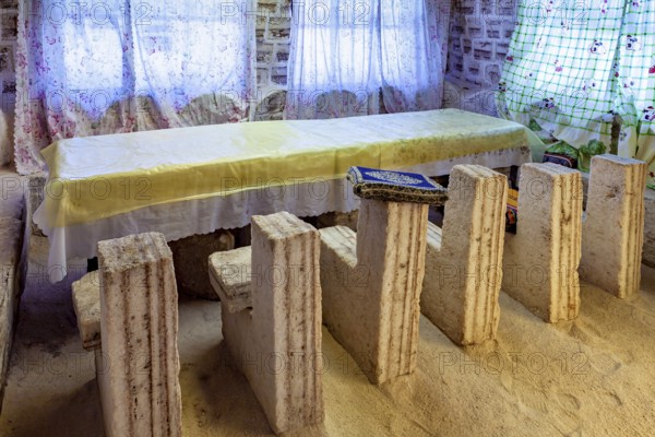 Long stone table with matching stone chair set in a bright, rustic room with patterned curtains, The salt hotel in the salt plain of the Salar de Uyuni in Bolivia