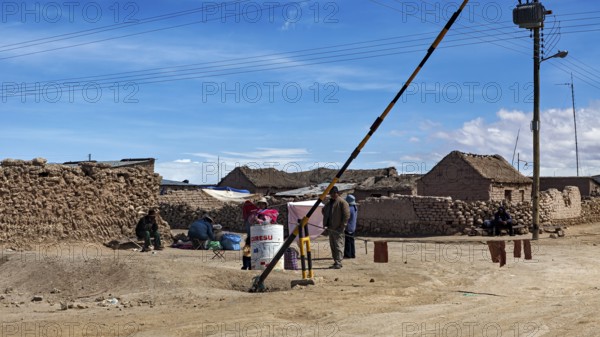 People in a desert town with clay-like buildings and a street lamp under a blue sky, A village on the Altiplano plateau in Bolivia
