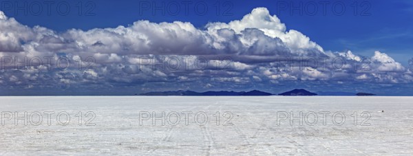 Wide cloud formation over a vast salt flat with distant mountain ranges, The endless expanses of the salt plain of the Salar de Uyuni in Bolivia