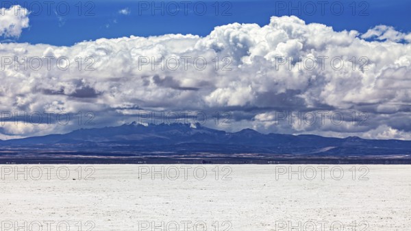 Majestic cloud formation over a flat, white salt landscape with a mountain backdrop, The endless expanses of the salt plain of the Salar de Uyuni in Bolivia