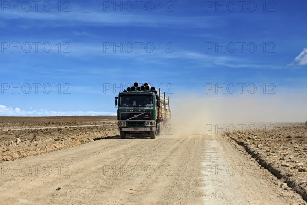 A lorry drives along a dusty road in an arid desert landscape, lorry drives through the highlands of the Altiplano in Bolivia
