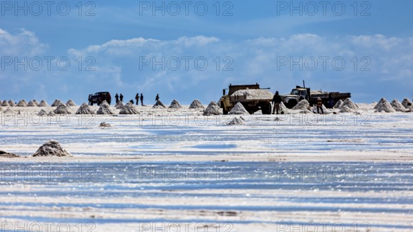 Vehicles and people move between salt hills on a shiny salt surface, The endless expanses of the salt plain of the Salar de Uyuni in Bolivia
