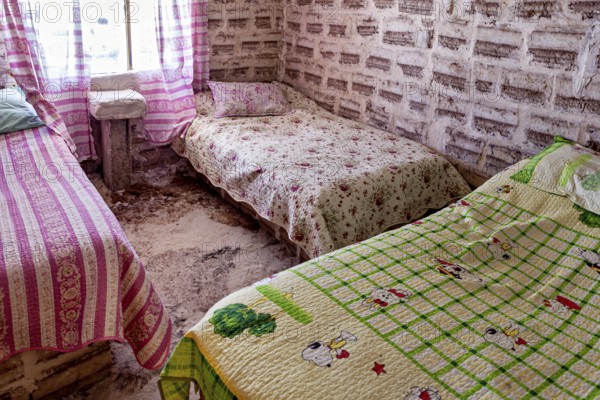 Rustic bedroom with patterned beds and pink and green-coloured textiles, The salt hotel in the salt plain of the Salar de Uyuni in Bolivia