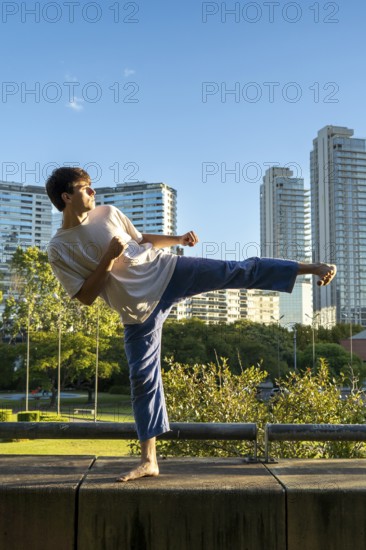Young man demonstrating a powerful kick in an urban setting