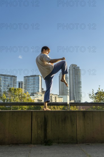 Young martial artist performing the crane pose in a modern city