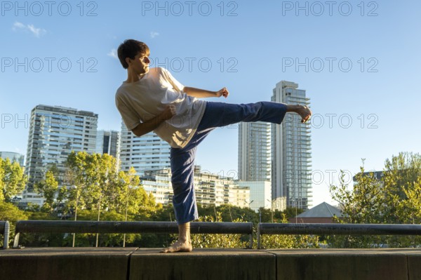 Young man demonstrating a powerful side kick in an urban setting