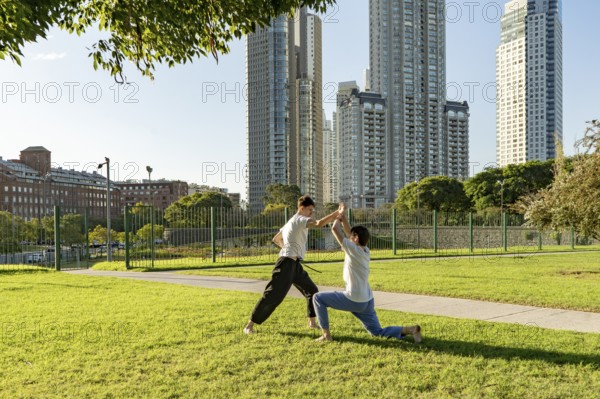 Two young men sparring in a park on a sunny day