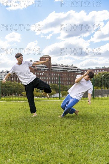 Two young men training martial arts in a green park