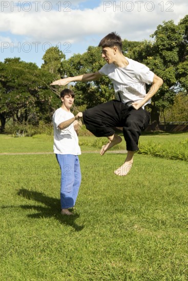 Young men practicing dynamic Taekwondo jumps in a park