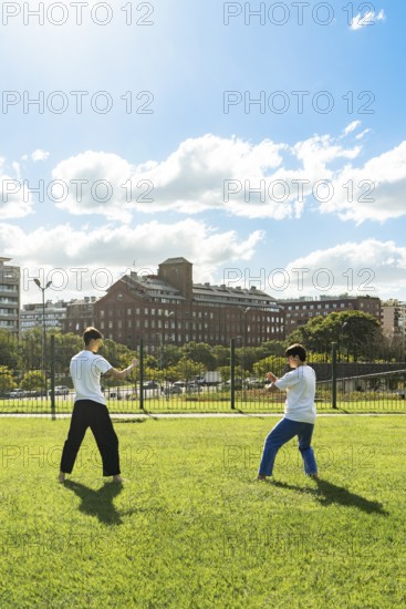 Two young men performing martial arts forms in a city park
