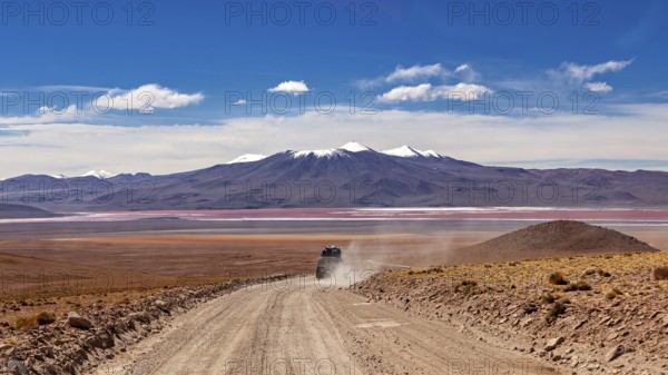 An off-road vehicle drives on a dusty road through a vast desert landscape with mountains in the background, The landscape of the Altiplano in Bolivia