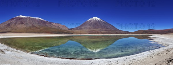 Broad mountain backdrop with two snow-covered peaks reflected in a calm lake, The Laguna Colorada in Bolivia