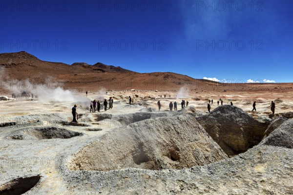 People at a smoking geyser in a vast desert landscape, The mud volcanoes and fumaroles on the Altiplano in Bolivia