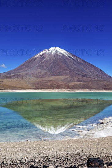 Striking volcano with a turquoise lake whose clear surface reflects the majestic mountain, The Laguna Colorada in Bolivia