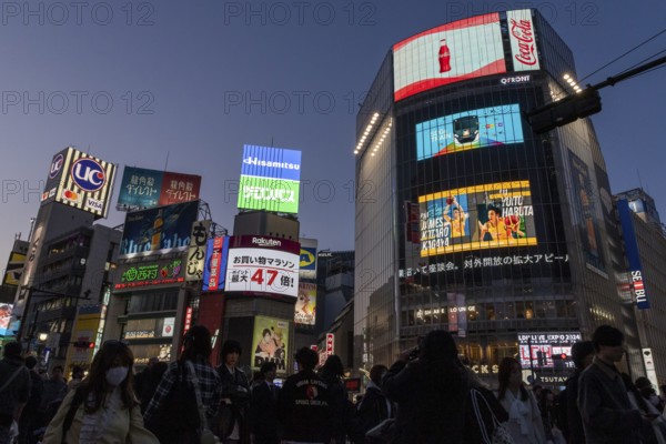Crowd crossing the zebra crossings of Shibuya Crossing, world-famous intersection in Shibuya district, behind it neon signs and billboards on skyscrapers at dusk, tourist attraction, landmark, Shibuya district, Tokyo, Japan