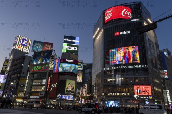Cars in traffic at Shibuya Crossing, world-famous intersection in the Shibuya district, behind it neon signs and billboards on skyscrapers at dusk, tourist attraction, sight, Shibuya district, Tokyo, Japan