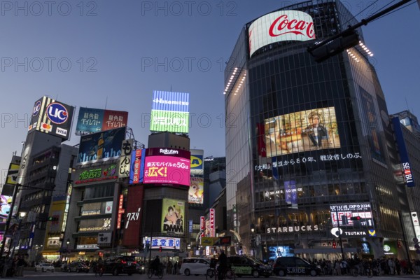 Cars in traffic at Shibuya Crossing, world-famous intersection in the Shibuya district, behind it neon signs and billboards on skyscrapers at dusk, tourist attraction, sight, Shibuya district, Tokyo, Japan