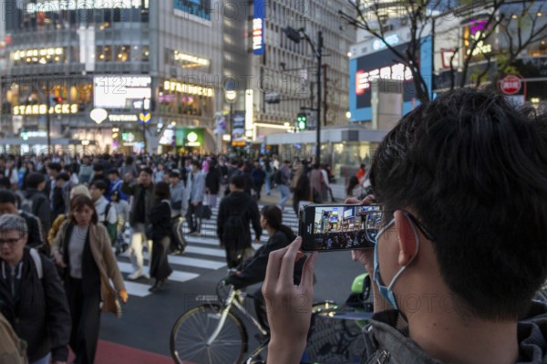 A tourist films the crowd at the zebra crossing of Shibuya Crossing with his smartphone, world-famous crossing in the Shibuya district, tourist attraction, sight, Shibuya district, Tokyo, Japan