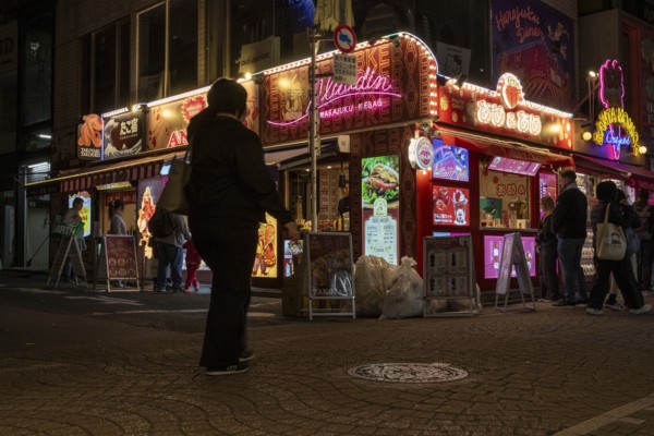 Tourists in front of a shop with illuminated advertisement for kebab and Japanese crepes in Takeshita-dori, Takeshita Street, alley with souvenir shops and restaurants in Harajuku neighbourhood at night, tourist attraction, sight, Shibuya district, Tokyo, Japan