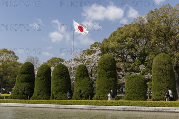 Japanese national flag and artistically trimmed hedges in the Peace Park, sight, UNESCO World Heritage Site, peace memorial and memorial to the victims of the atomic bombing of Hiroshima, Naka Ward, Hiroshima, Japan
