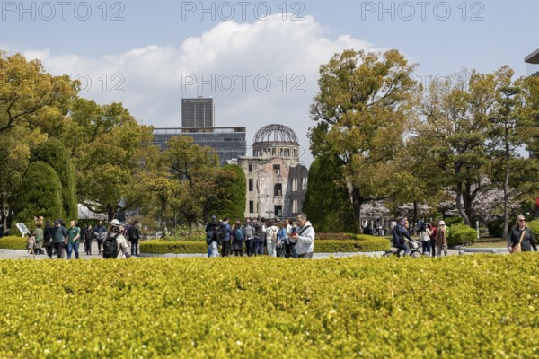 Tourists in the Peace Park with a view of the ruins of the Atomic Bomb Dome, landmark, UNESCO World Heritage Site, peace memorial and memorial to the victims of the atomic bombing of Hiroshima, Naka Ward, Hiroshima, Japan