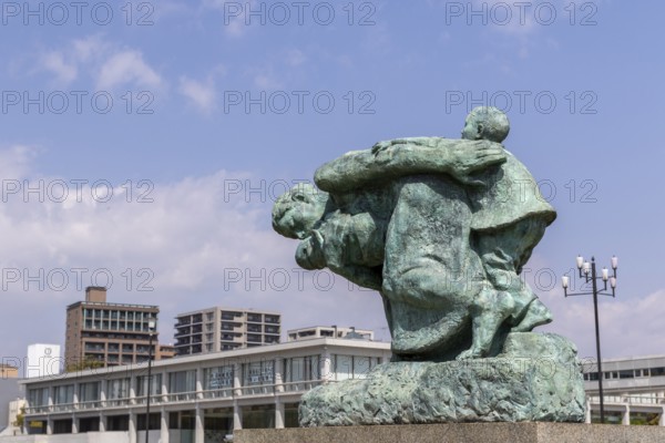 Statue of mother and children in the storm, bronze statue by the artist Shin Hongo in front of the Hiroshima Peace Museum, landmark, UNESCO World Heritage Site, peace memorial and memorial to the victims of the atomic bombing of Hiroshima in the Peace Park, Naka Ward, Hiroshima, Japan